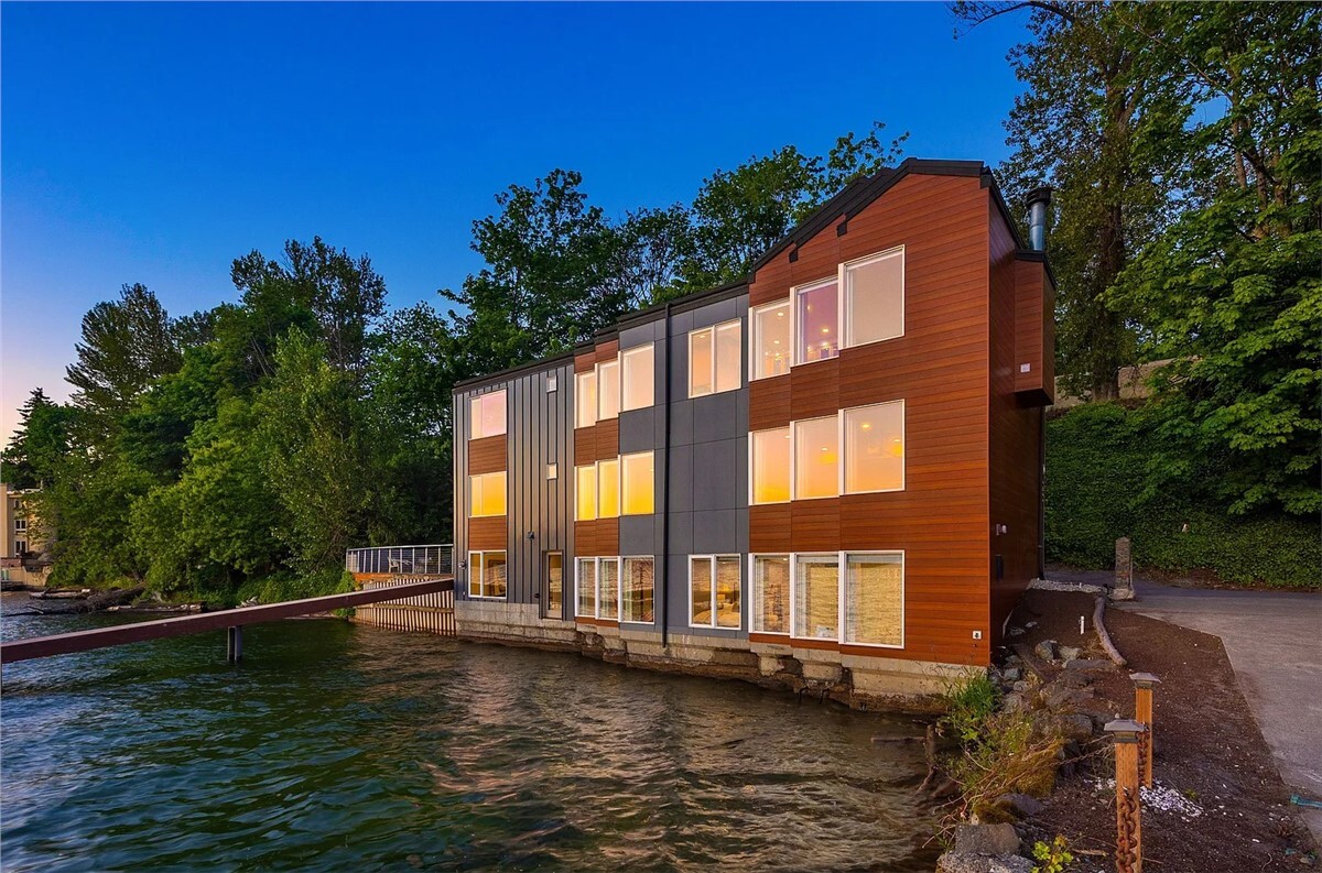 An apartment building with red and gray metal siding on a waterfront