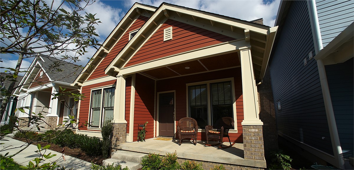 A house with red siding and cream columns and trim