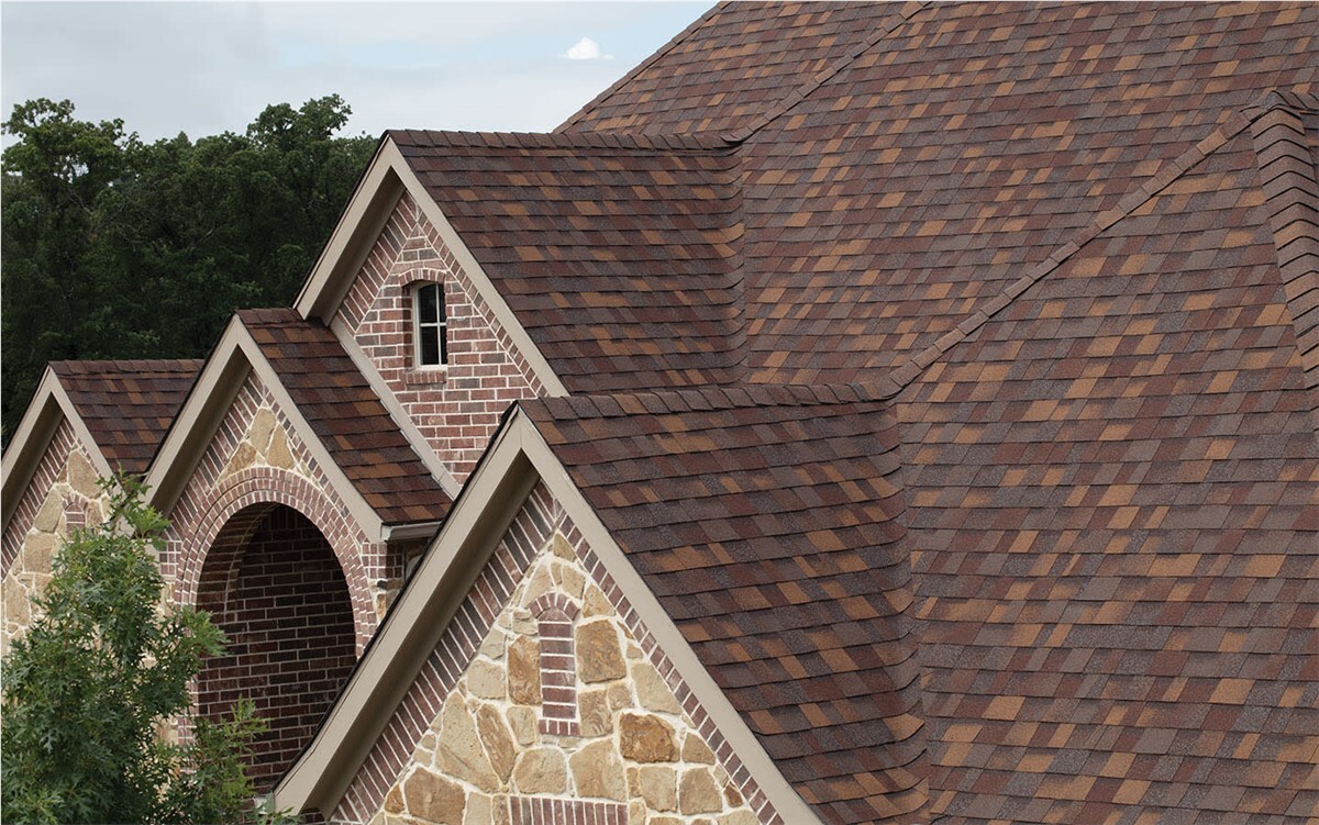 Close up of brown asphalt shingle son a house with stone and brick siding