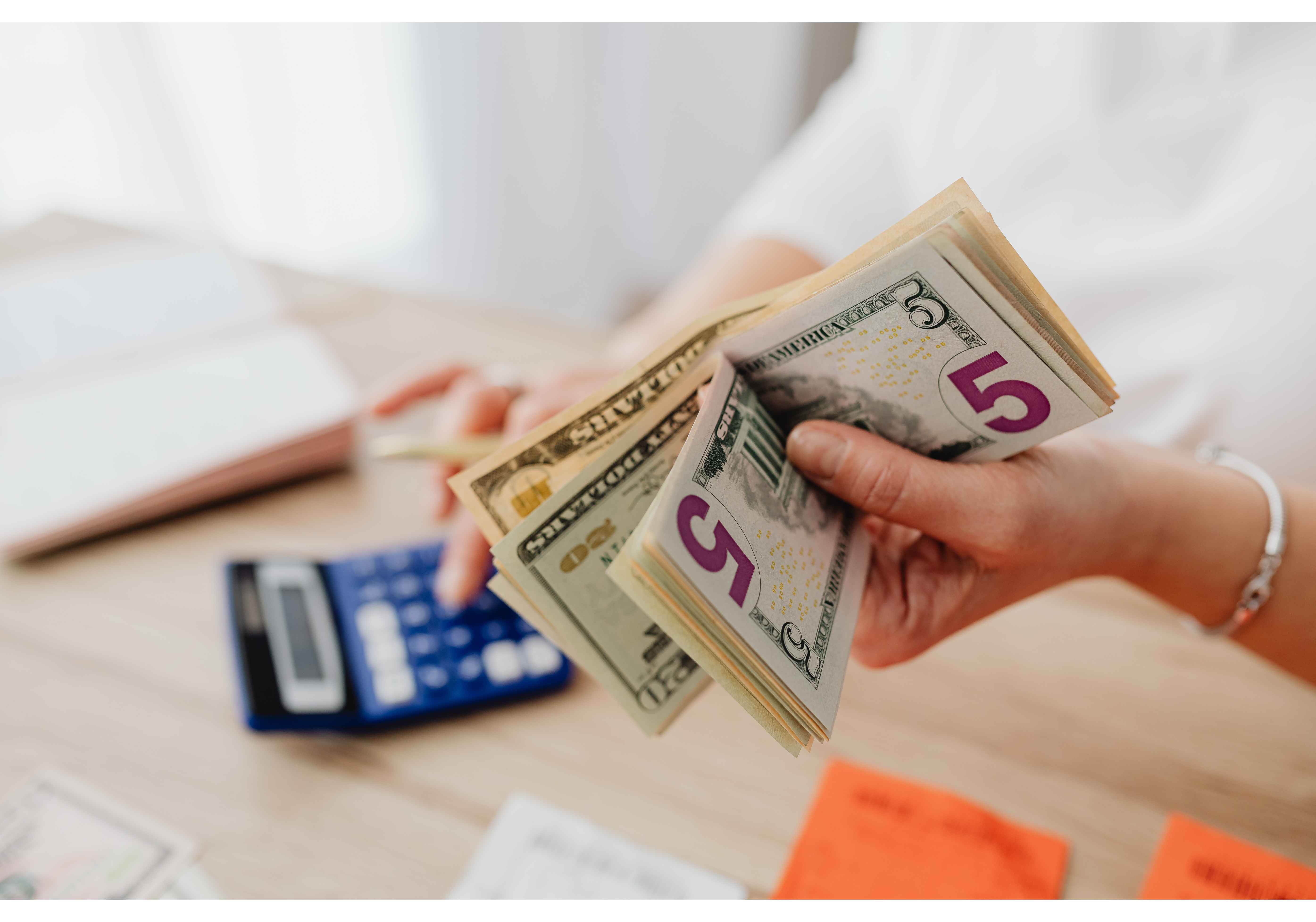 Holding-dollar-bills-while-paying-bills